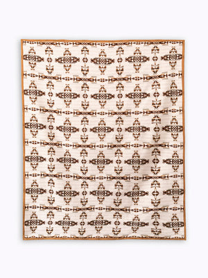 Flay lay of white and brown mother and child blanket with geometric celtic symbol reinterpreted, it's a repeat pattern
