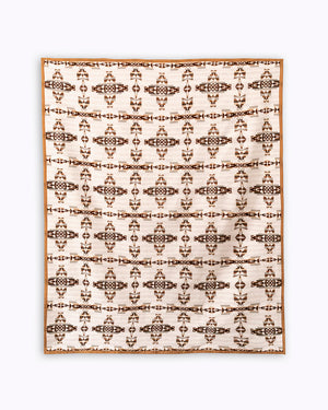 Flay lay of white and brown mother and child blanket with geometric celtic symbol reinterpreted, it's a repeat pattern