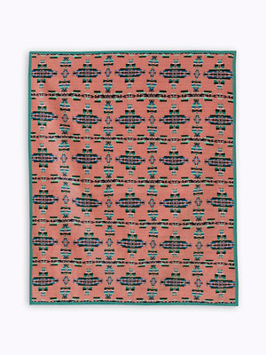 Pick background blanket with geometric green and dark green patterns that resemble crosses, 5 across and 6 vertically. Crosses are made from the Celtic mother and child symbol reimagined geometrically with corners